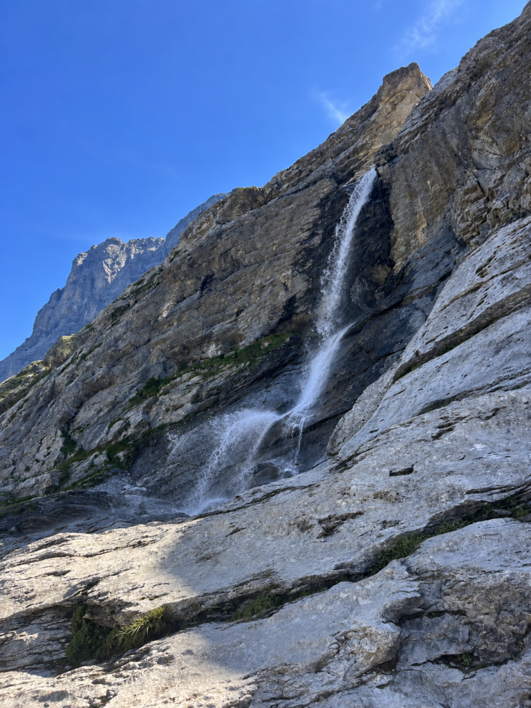 Waterfall flowing down the rocky mountain slope along the Eiger Trail